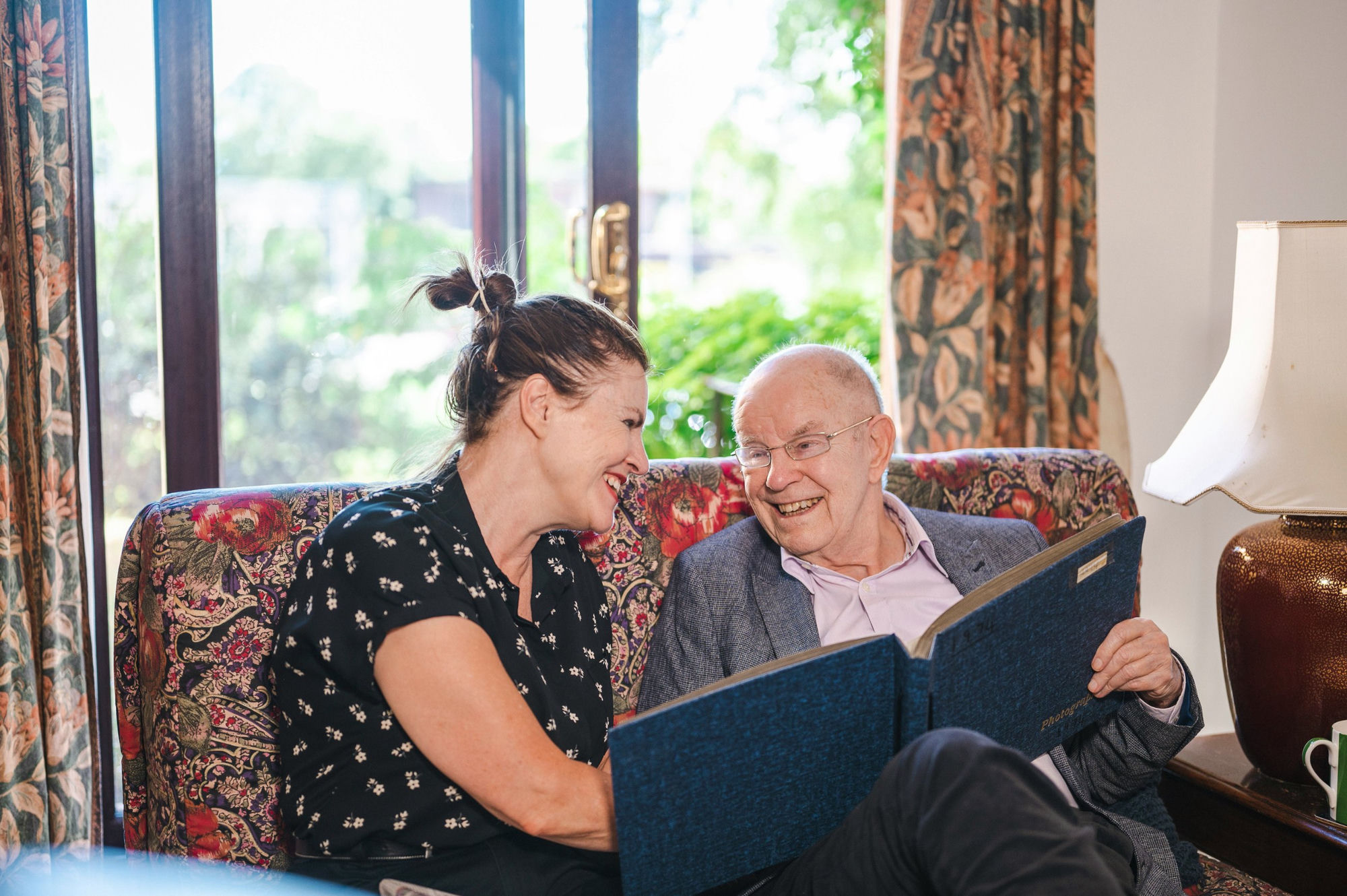 A caregiver laughing with a resident while looking through a photo album