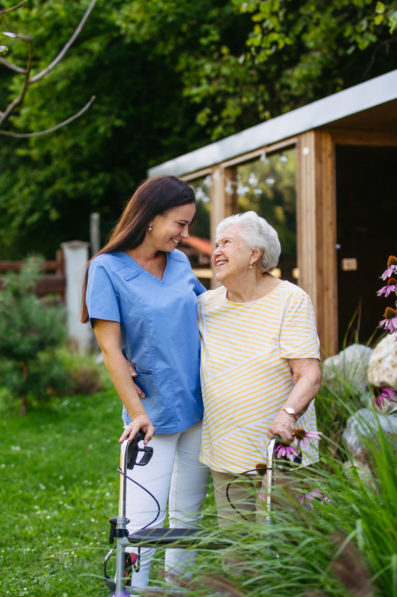 A caregiver walking with a smiling resident in the garden